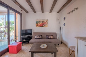A living room with a sofa, a coffee table, a TV, and a painting on the wall.