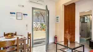 Una hall d'albergo con area ristorazione, un tavolo in vetro, un estintore e una porta in legno.
