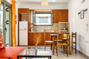 A compact kitchen with a refrigerator, sink, and dining area with chairs.