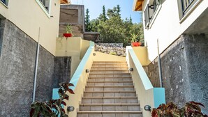 Una scala conduce a un edificio con un muro in pietra e piante in vaso.