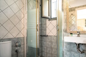 A bathroom with a glass shower enclosure, a white sink, and a tiled floor. - Holiday Accommodation "Alkionides Apartment 1" with pine forest overlook (Lefkada)