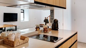 Una cuina moderna amb vitroceràmica, cafetera i brosses decoratives al taulell.