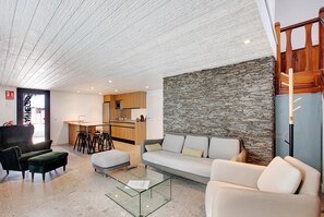 A modern living room with a sofa, ottoman, and glass coffee table.