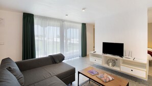 Una sala de estar moderna con un sofá, una mesa de centro, un televisor y un mueble blanco para entretenimiento.