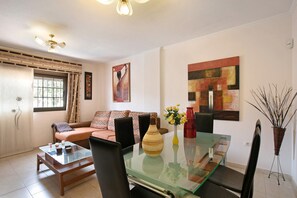 A living room with a glass-top dining table, a sofa, and a coffee table.