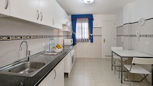 Una cocina con fregadero, microondas y comedor con sillas.
