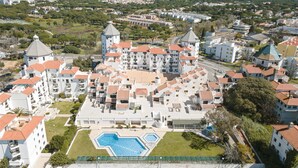 Ein großer Hotelkomplex mit mehreren Gebäuden, einem zentral gelegenen Schwimmbad und umgebender Grünfläche.