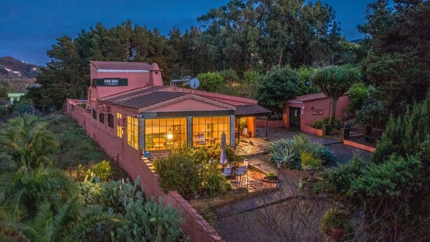 Una casa de dues plantes amb una zona de pati, envoltada de vegetació.