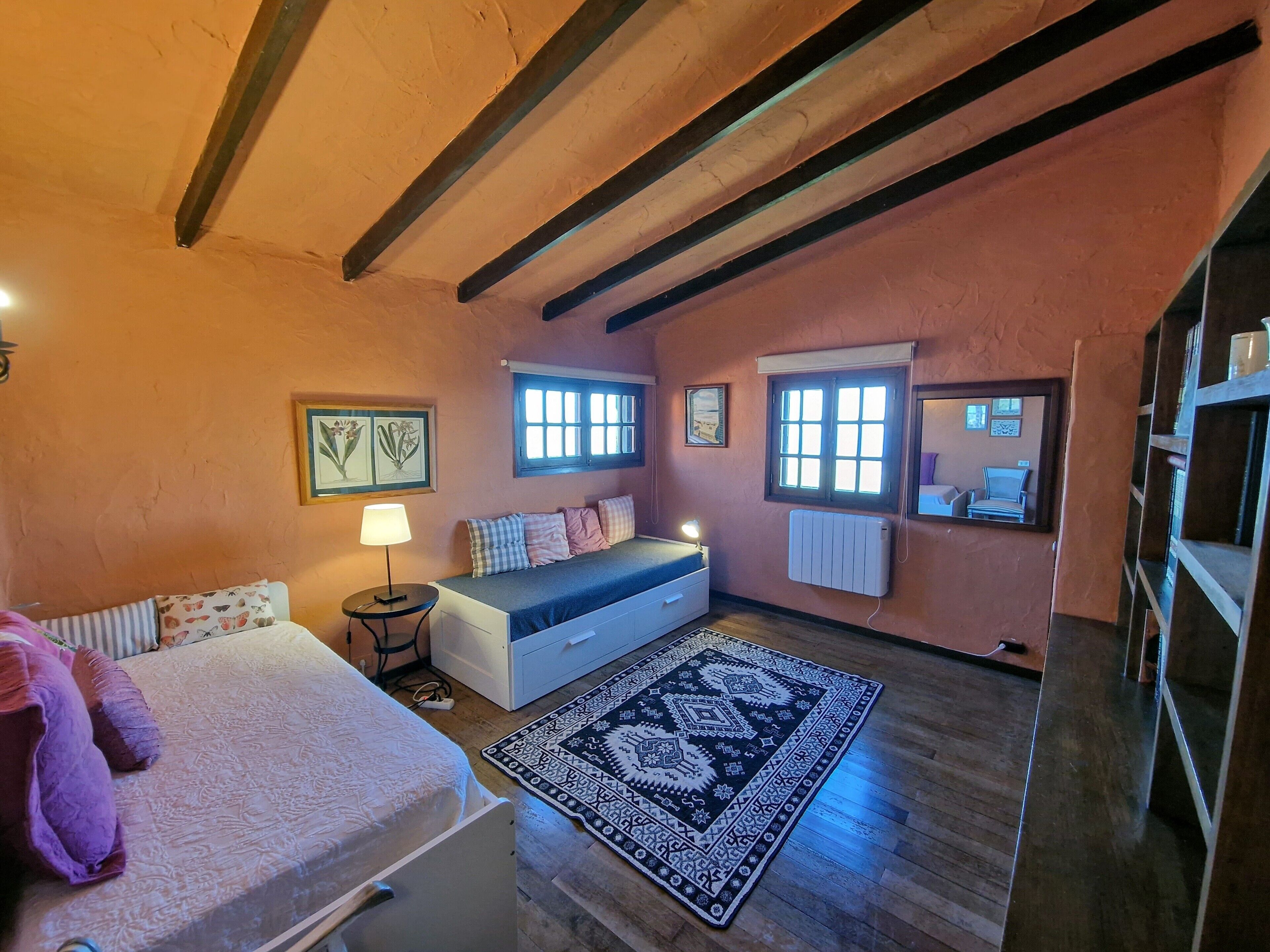A cozy bedroom with a bed, bedside table, lamp, and a patterned rug.