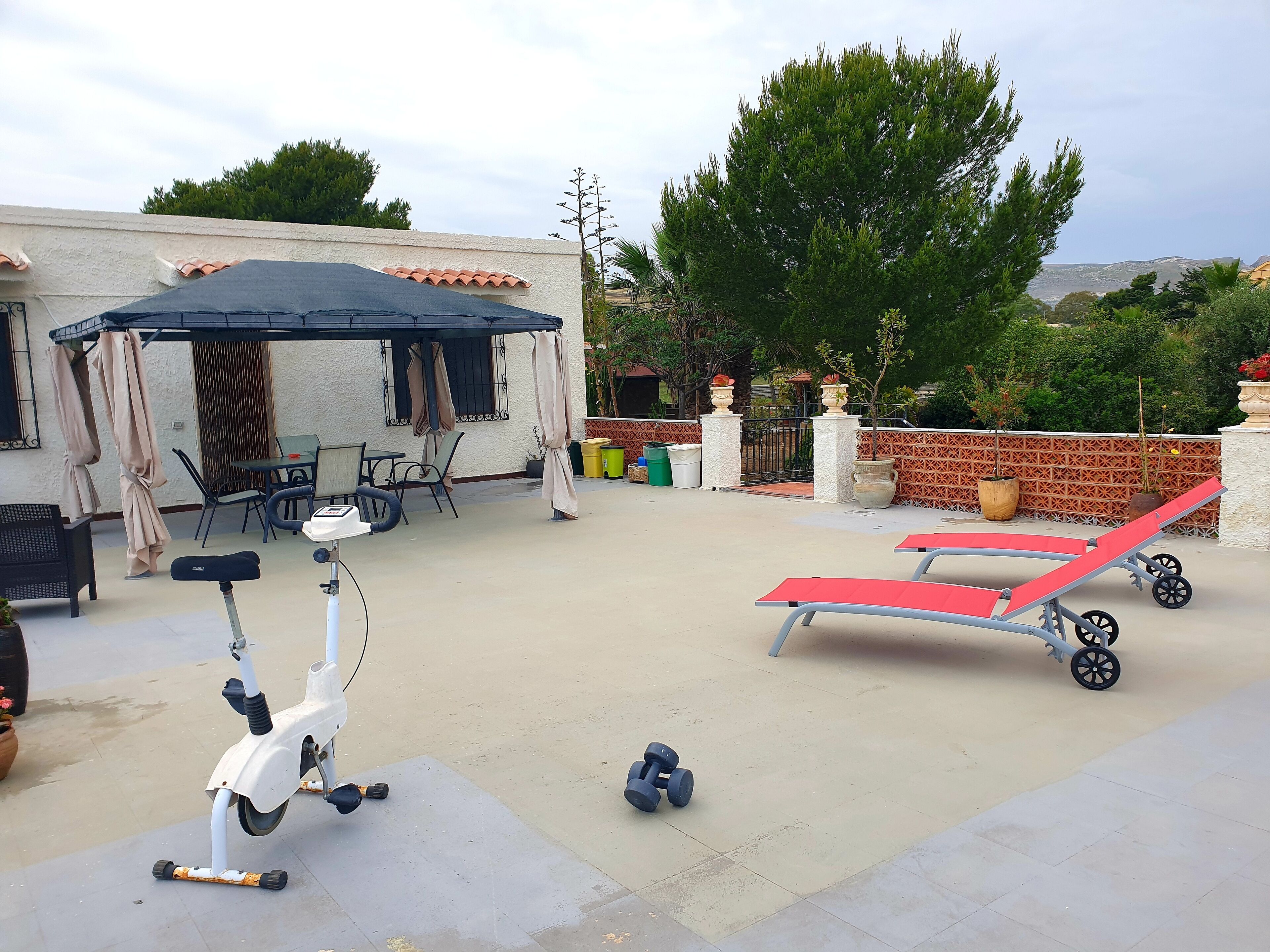 Uma área de pátio com móveis de exterior, uma scooter e equipamentos de ginástica.