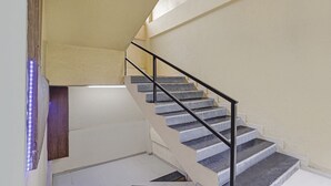 A staircase with a black handrail and white walls. - New Harshita inn By Glitz Hotel  (Navi Mumbai)