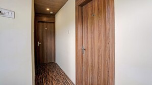 A hallway with wooden doors and a patterned floor. - New Harshita inn By Glitz Hotel  (Navi Mumbai)
