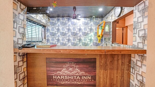 A reception desk at Harshita Inn with a patterned wall, a ceiling fan, and a clock. - New Harshita inn By Glitz Hotel  (Navi Mumbai)