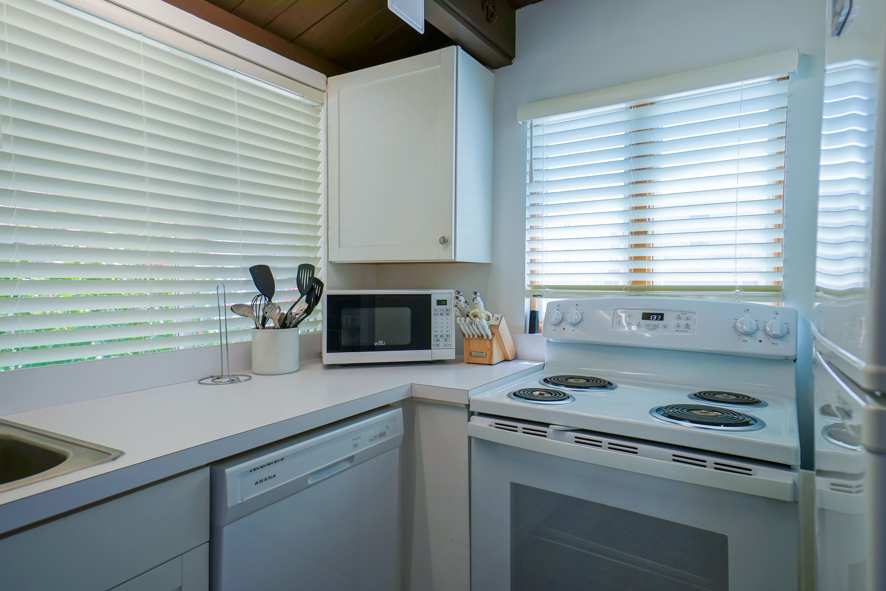 Une cuisine équipée d’appareils électroménagers blancs, notamment un four à micro-ondes, une cuisinière et un lave-vaisselle.