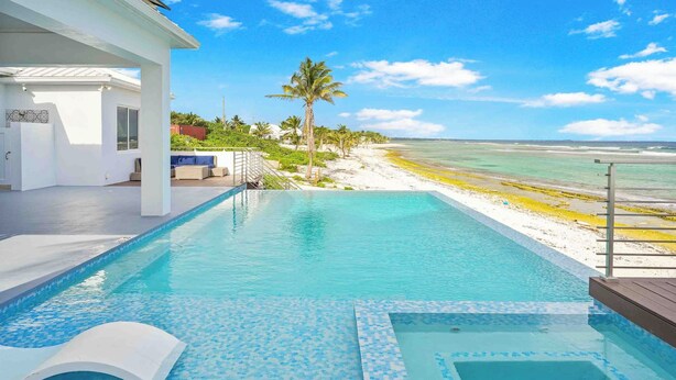 A pool area with a view of the beach and ocean.