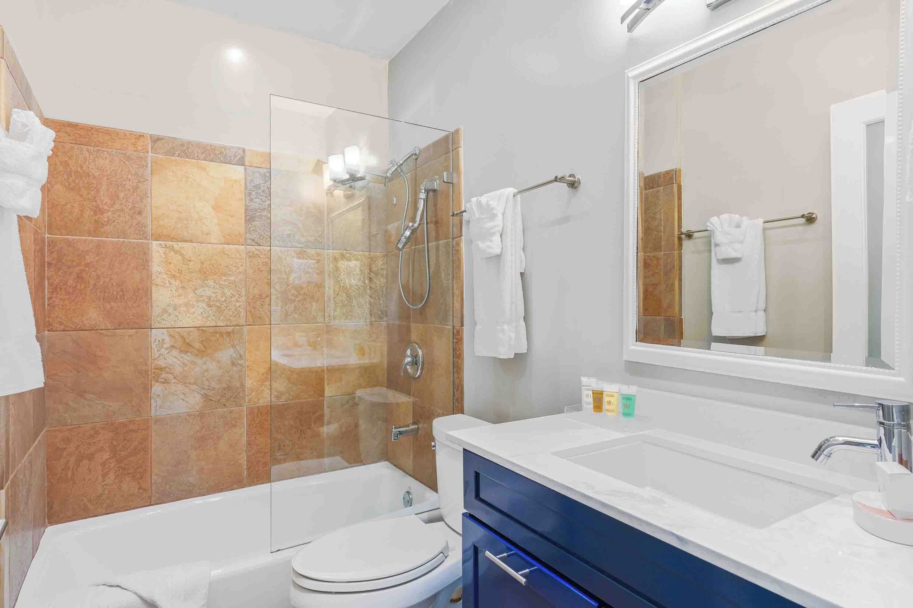 Un baño moderno con ducha envuelta en vidrio, inodoro blanco y tocador con espejo.