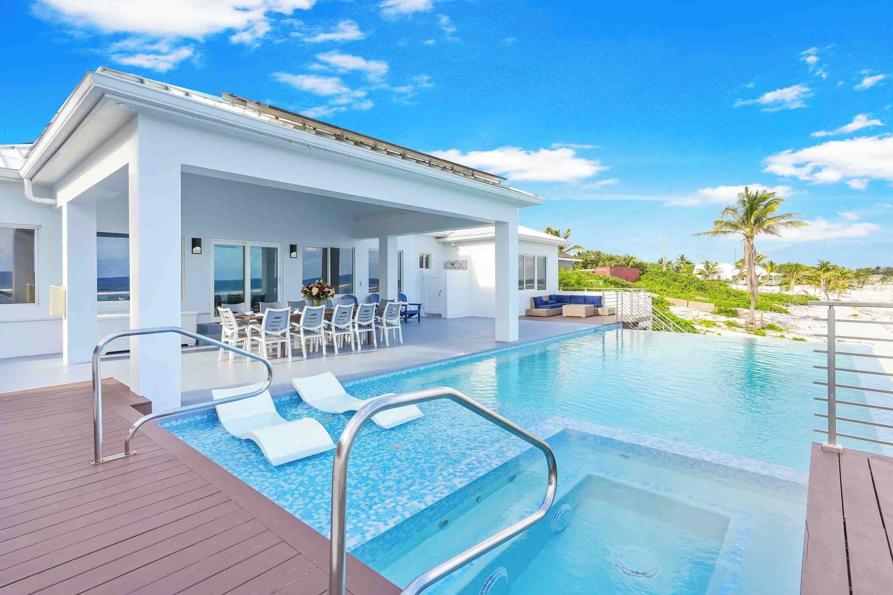 A modern hotel with a pool area, outdoor seating, and a view of the beach.