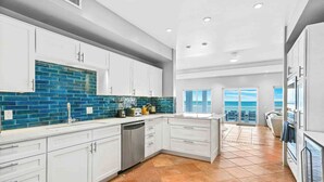 A modern kitchen with white cabinets, a blue-tiled backsplash, and a dishwasher.