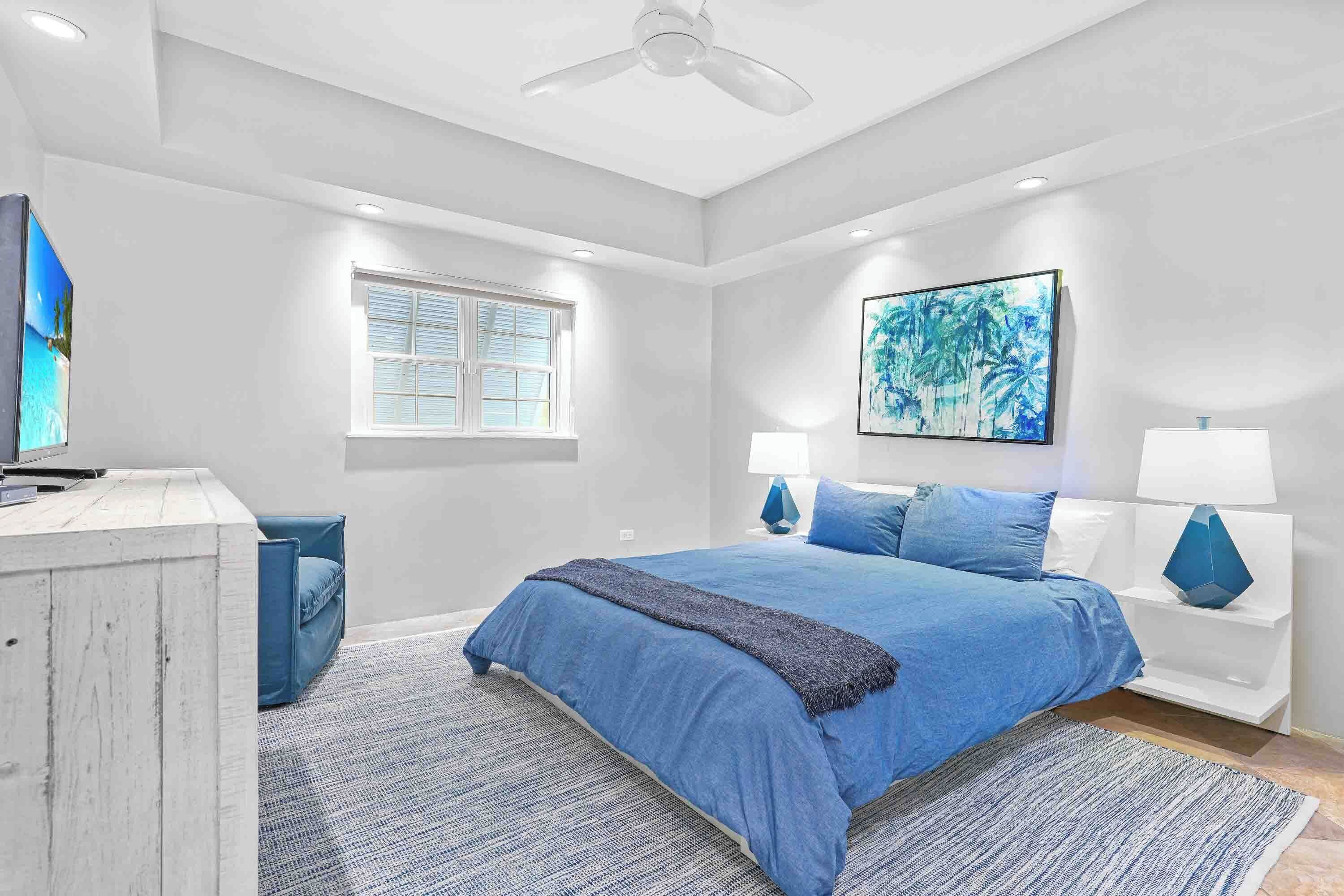 Quarto com cama, escrivaninha, cadeira, janela e ventilador de teto.
