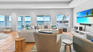 A spacious living room with a large flat-screen TV, a sofa, and a coffee table.