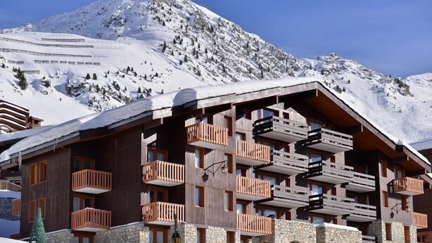 A wooden chalet with multiple balconies, set against a snowy mountain backdrop. - 100m from ski slopes, 3rd floor, view ski slopes/ski slopes, balcony, tv, 28m², La Plagne (La Plagne)