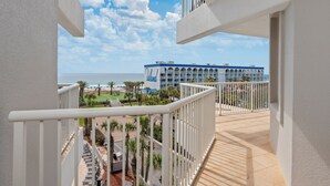 Hotel met balkon met uitzicht op strand en zwembad.
