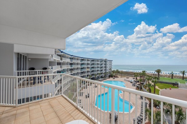 Un balcone d'hotel con vista su una piscina, una spiaggia e l'oceano.