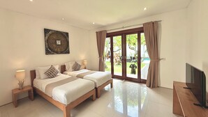 A hotel room with two beds, a TV, and a sliding glass door to a garden. - NIL VILLA SEMINYAK - 3 BEDROOMS (Bali)