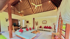 A spacious living area with a sofa set, a dining table, and a kitchen in the background. - NIL VILLA SEMINYAK - 3 BEDROOMS (Bali)