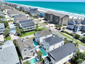 A coastal residential area with houses, a swimming pool, and a beach in the background.