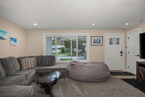 A living room with a sectional sofa, a bean bag, a coffee table, and a television.