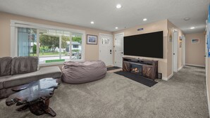 A living room with a flat-screen TV, a fireplace, a bean bag, and a sofa.