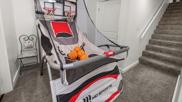 A home basketball court with a net, a chair, and a staircase.