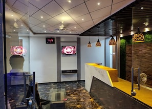Ett receptionsområde med en marmorskiva, en digital klocka och en modern takdesign.