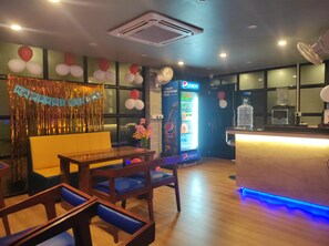 Interior de restaurante con un cartel de 'Happy Birthday', un refrigerador de Pepsi, mobiliario de madera y una barra iluminada en azul.