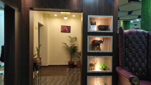 Zona de recepción con un mostrador de madera oscura, una butaca de cuero rojo y un expositor mural con figuras de animales y plantas.