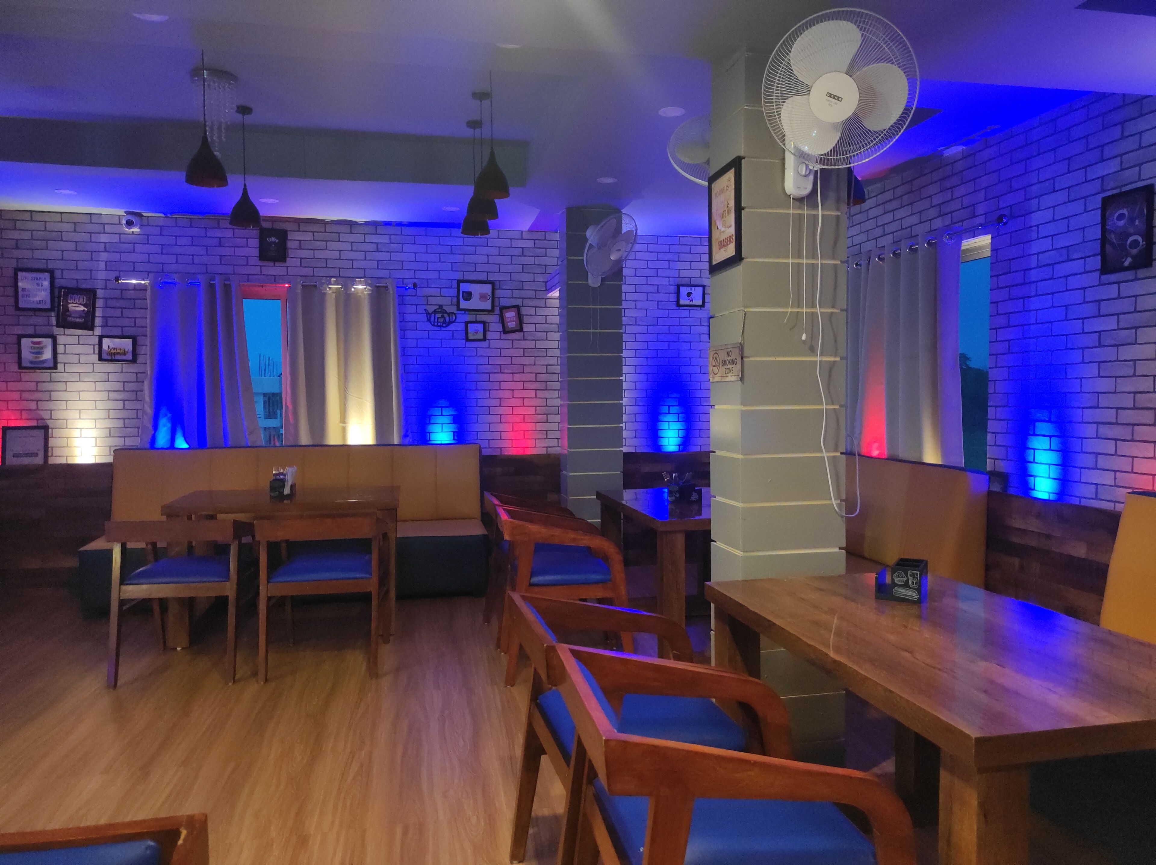 Een restaurant met bakstenen muren, houten meubels en blauwe lichtaccenten.