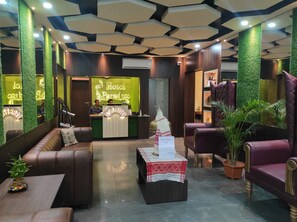 Zona de recepción de hotel con pared verde, mostrador de recepción, asientos de cuero y un letrero de evento de Star Cement.