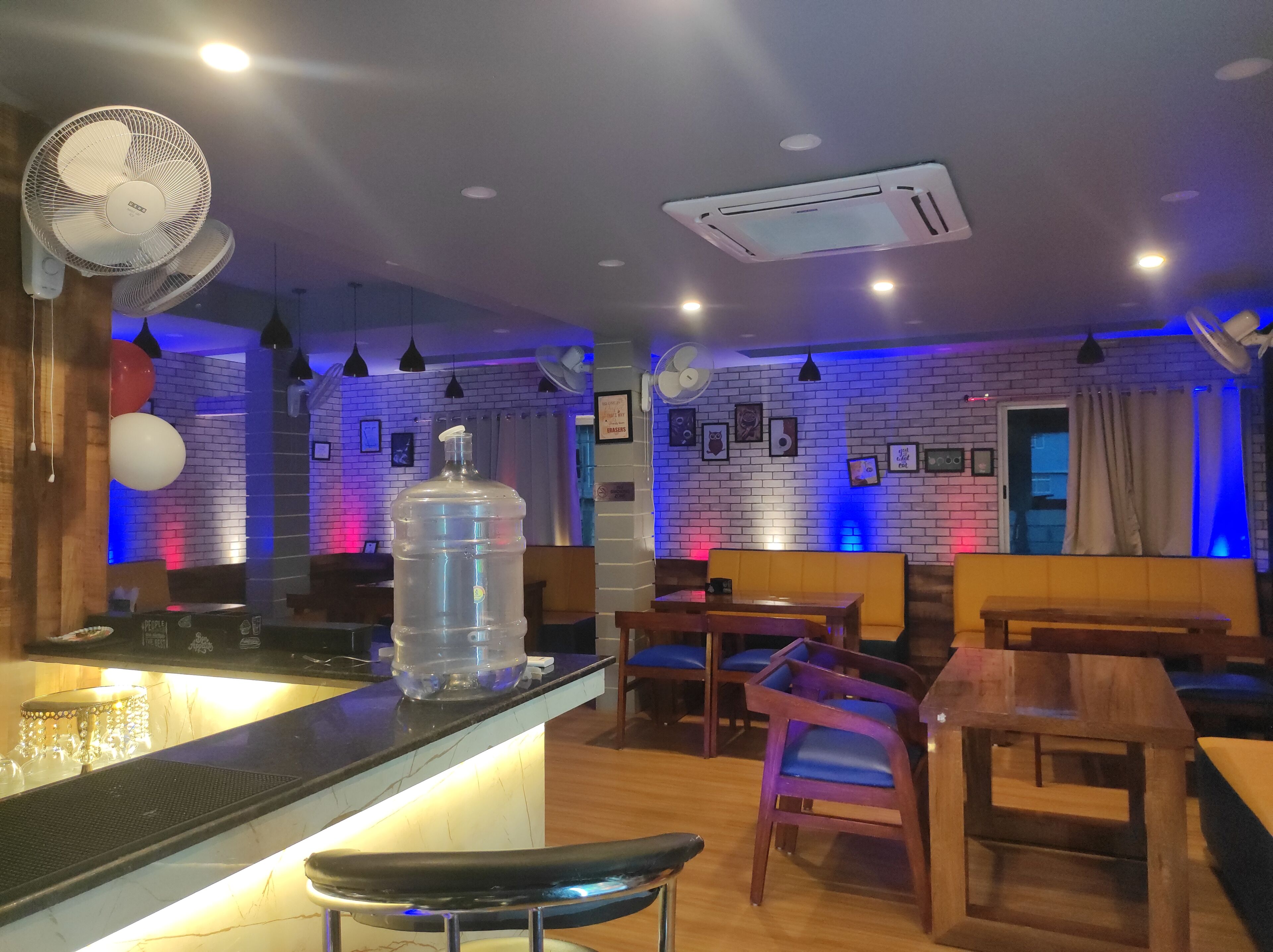 Interior de restaurante con paredes de ladrillo, mobiliario de madera y un dispensador de agua.