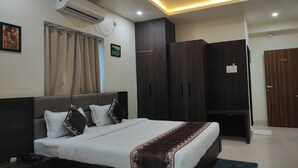 Una habitación de hotel con cama, armario, aire acondicionado y ventilador de techo.