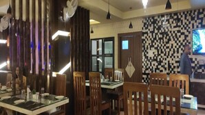 Un interior de restaurante con sillas y mesas de madera, y un patrón de pared a cuadros.