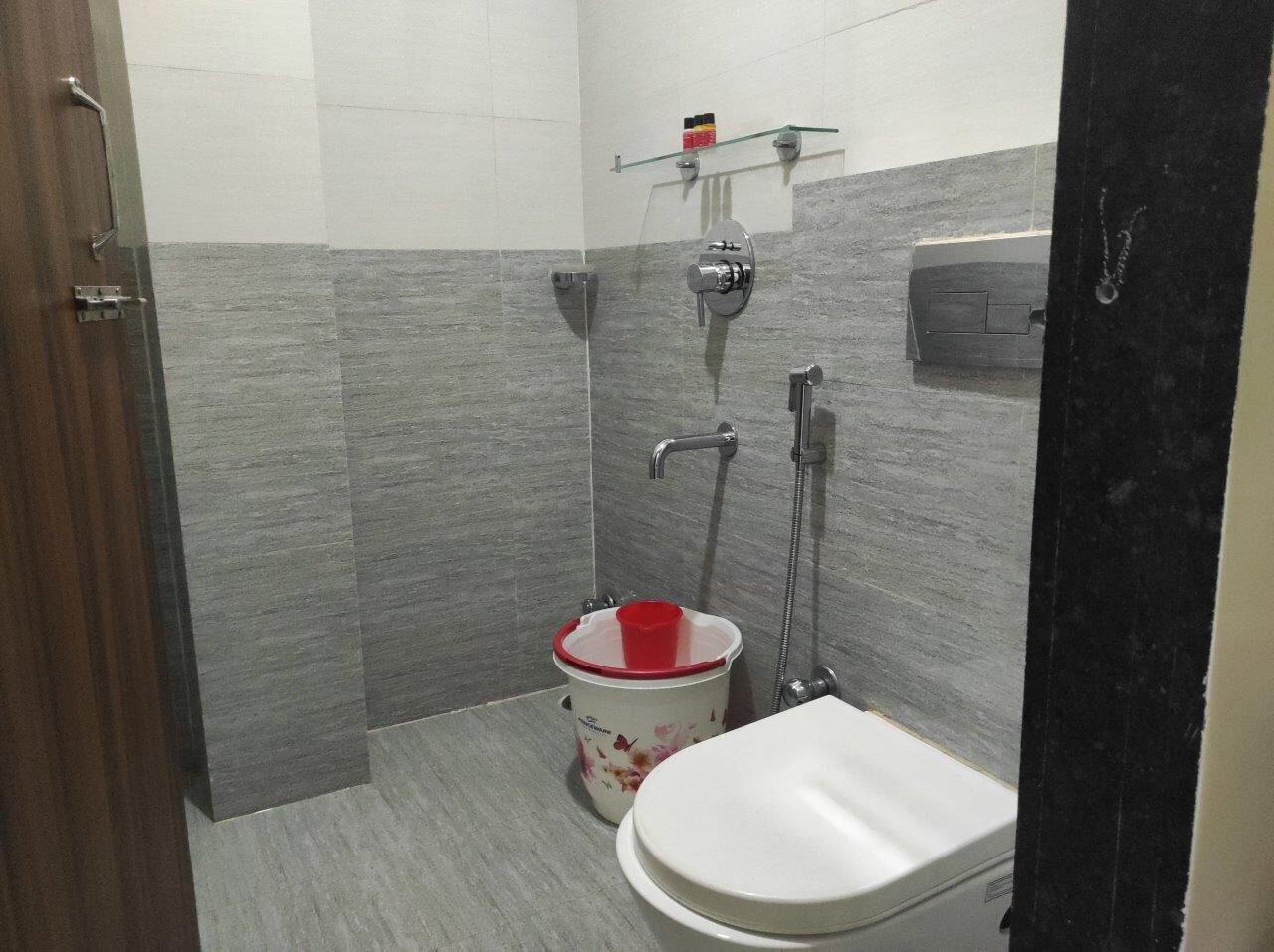 Et lille badeværelse med toilet, bruser og håndvask.