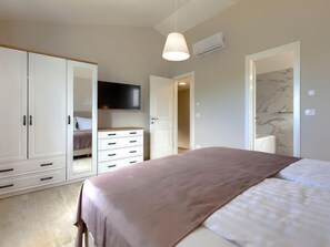Ein Schlafzimmer mit Bett, Kleiderschrank, Fernseher und Klimaanlage.