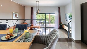 A modern dining area with a wooden table, chairs, and breakfast items. There is a balcony with a view of greenery. - Villa Bella by Interhome (Novigrad (Istra))