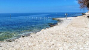 A coastal walkway with clear blue sea, stone pavement, and a few birds in the distance. - Villa Bella by Interhome (Novigrad (Istra))