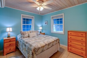 A bedroom with a bed, two nightstands, a wooden dresser, and two windows with blinds. - Elbow Joint: Comfortable Island Escape in White Sound near Firefly Resort (Hope Town)