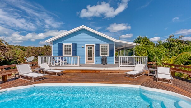 Una casa azul con terraza de madera y piscina.