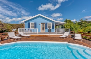Una casa azul con terraza de madera y piscina.