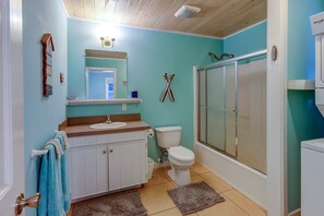 A bathroom with a toilet, sink, and shower. There is a towel rack with towels, a mirror, and a shelf with toiletries. - Elbow Joint: Comfortable Island Escape in White Sound near Firefly Resort (Hope Town)