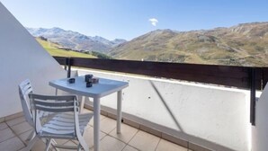 Een balkon met een tafel en stoelen, met uitzicht op een bergachtig landschap.
